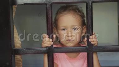 肖像小女孩看着窗外，从外面慢镜头拍摄