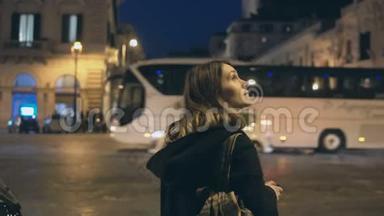 背着背包的年轻旅游妇女站在交通道路上，晚上四处张望。