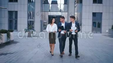 成功的商业人士在中央商务区讨论商业和步行。 两名青年男子和一名女子