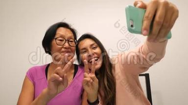 年长的母亲和年轻的混合种族女儿用<strong>手机制作</strong>有趣的自拍照片。 4K.