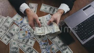 一个商人坐在办公室的桌子上数着钱，紧紧地握住他的手。 <strong>薪酬</strong>或利润的概念..