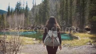 女徒步旅行者在<strong>湖边</strong>漫步，欣赏他壮观的<strong>景色</strong>。 在茂密的松林的背景下