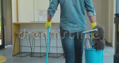 男人拿着拖把和<strong>塑料桶</strong>，厨房里有刷子，手套和洗涤剂。