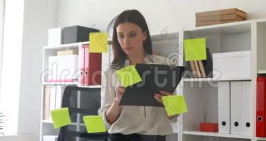 女商人站在玻璃墙附近的文件里做笔记。