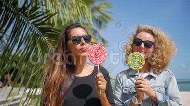 美丽的混合种族海普斯特女孩`在热带海滩舔棒棒糖和微笑。 高清慢速运动。 戈芬加
