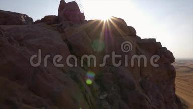 清晨阳光洒在岩石山上，背景是沙漠中的沙丘