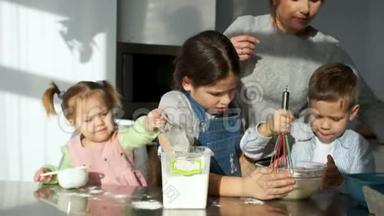 三个不同年龄的孩子揉面团。 姐姐把面粉放在碗里。 妈妈在后台管理