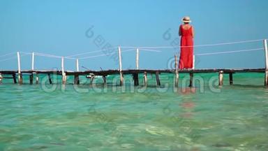 穿着红色长裙的女人.. 这位穿红色衣服的年轻女子在码头上<strong>花钱</strong>，远远地看着。 岛上阳光明媚的一天