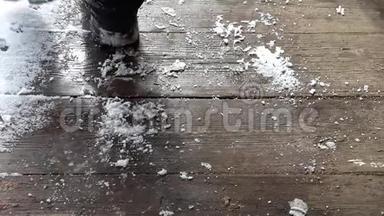 穿着黑色皮靴的人在木地板上踩着雪