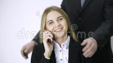 女商人在打电话时，雇员做了很长时间的工作后，会按摩她的肩膀和脖子