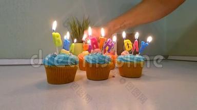 多种颜色的<strong>纸杯</strong>蛋糕和蜡烛，以纪念生日聚会。 年轻人的手在<strong>纸杯</strong>蛋糕上点燃蜡烛。 慢动作