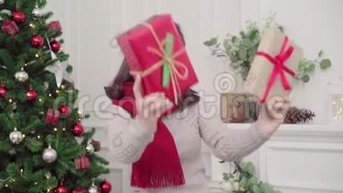 圣诞佳节，快乐的年轻亚洲女人在家的客厅里，捧着圣诞礼物微笑着拍照。
