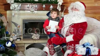 圣诞老人腿上的小男孩在<strong>诉说</strong>`的圣诞祝福，小男孩在圣尼古拉斯的冬居