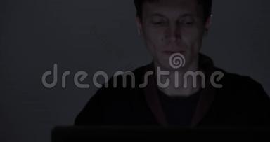 一个疲惫的男人<strong>深夜</strong>在黑暗的房间里用笔记本电脑<strong>工作</strong>的肖像