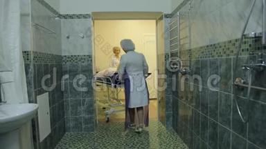 三个女护士把一个久坐不动的病人送到专门的房间去洗