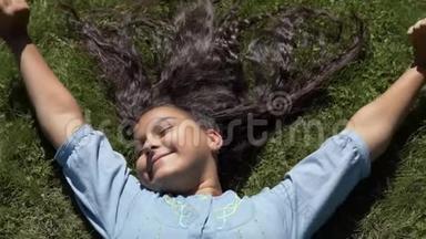 漂亮的长发女孩躺在公园的草地上。慢动作。 高清高清