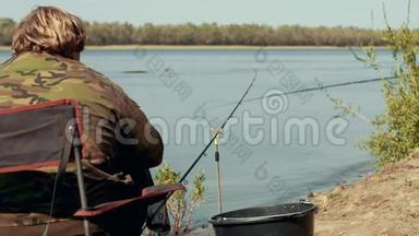 渔夫坐在河边的椅子上，几乎是钓竿，等待着咬人的背影