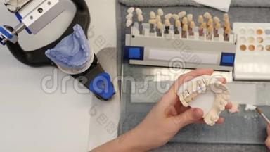 口腔科医生在<strong>工作间</strong>的餐桌上制作人造牙齿的牙套并在其上涂上白色着色剂