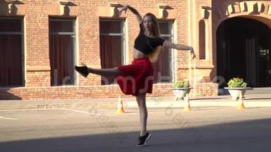 一个美丽的女孩，一头长发，穿着红色的裙子，在一座由红砖砌成的建筑外围的城市广场上跳舞