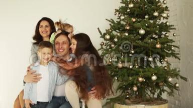 一个有三个孩子的大家庭在新年树附近拥抱。 圣诞快乐，新年快乐