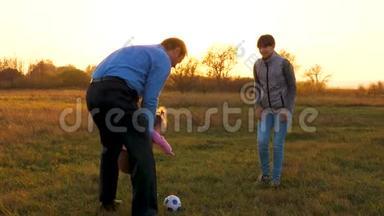 日落时分，一家人在公园里和小宝宝玩足球。 快乐爸爸和孩子踢皮球.. 幸福家庭