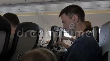 年轻人通过手机在耳机上听音乐。 一个商人正在飞机上看一段视频