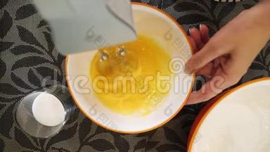 用电动搅拌器在碗中搅拌蛋黄的顶部视图。