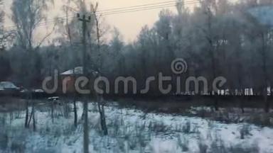 火车从窗口观看冬季雪林村房屋在雪。 冬天的森林透过窗户