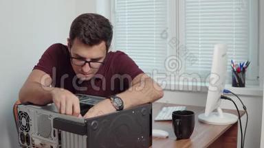 年轻的专业工人用螺丝刀修理办公室里的一台坏电脑，并升级电脑硬件