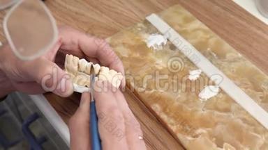 在木制工作台上制作种植牙、人工牙齿上涂陶瓷釉的人手臂