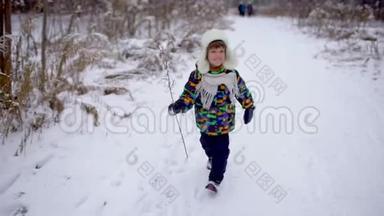 冬天，一个非常可爱快乐的小男孩在公园里跑步。 冬天的时候。 快乐的男孩在雪地冬季公园玩得很开心。 他是