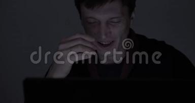 一个疲惫的男人深夜在黑暗的房间里用笔记本电脑工作的肖像