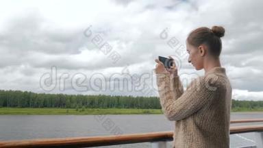女用智能手机在游轮甲板上拍照
