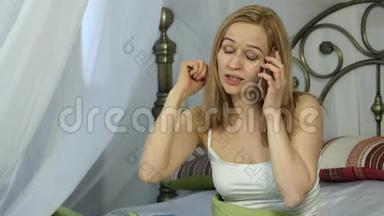 情绪化的美丽金发女人在床上打电话唱歌。 4K