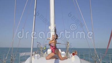 一位身穿泳装的<strong>豪华</strong>黑发女郎跪在<strong>游艇</strong>中间，挽着她的头发，享受着阳光明媚的天气，慢慢地。