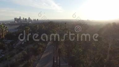 惊人的空中无人机剪辑洛杉矶和阳光背后的公园树