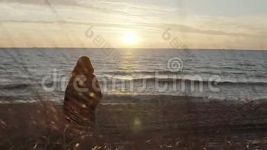 海边有格子花格子的年轻女子的后景，眺望远方.. 日落时分在海滩上的一个女人。