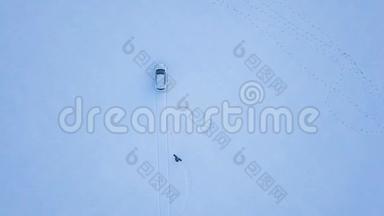 从高处到人的视野是在一个雪覆盖的田野上，在一辆汽车后面的电缆上骑着一块滑雪板