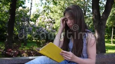 可爱的<strong>少女</strong>坐在公园的长凳上<strong>看书</strong>，在户外学习。高清视频静态画面拍摄