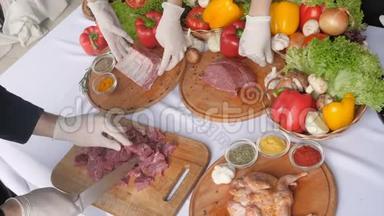 男厨师在餐厅厨房的木板上切大块牛肉。 男人做饭，准备牛排和蔬菜