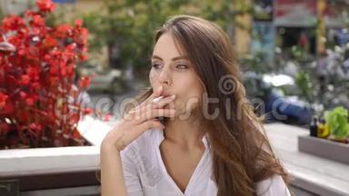昏黑的黑发女人在红花前<strong>坐在餐馆</strong>里抽雪茄