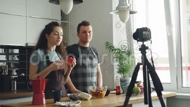 快乐有吸引力的一对夫妇在家里用数码相机录制关于健康烹饪的视频食物