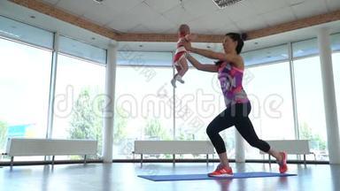 <strong>夏天</strong>，妈妈抱着一个<strong>小孩</strong>在健身房的地毯上做热身运动，动作缓慢