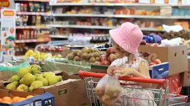 商店里的小女孩选水果。杂货超市和购物车