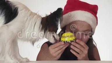 美丽的少女，戴着圣诞老人的帽子和狗——大陆玩具——斯帕涅尔——帕皮隆，胃口大开，吃起来很高兴