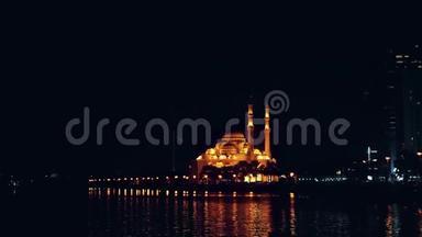 夜景照明与金灯清真寺在海滨。 惊涛拍傍晚海滨.. 大城市的灯光。