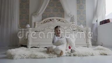 一个迷人的女孩坐在床边的地板上，<strong>快</strong>乐地玩着柔软的泰迪熊。 <strong>快</strong>乐的<strong>宝宝</strong>和她的泰迪熊