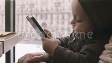 孩子在桌子上<strong>玩手机</strong>。 婴儿手在咖啡馆的智能<strong>手机</strong>上发短信。 一个男孩坐在桌子旁