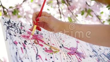 特写，女手，画家，画家，画家在盛开的春苹果园画了一幅花的画，她涂上了油