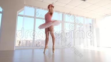 穿着粉色芭蕾舞裙的迷人女芭蕾舞演员在练习和微笑